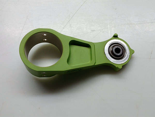 A green plastic part with a metal ring on it.