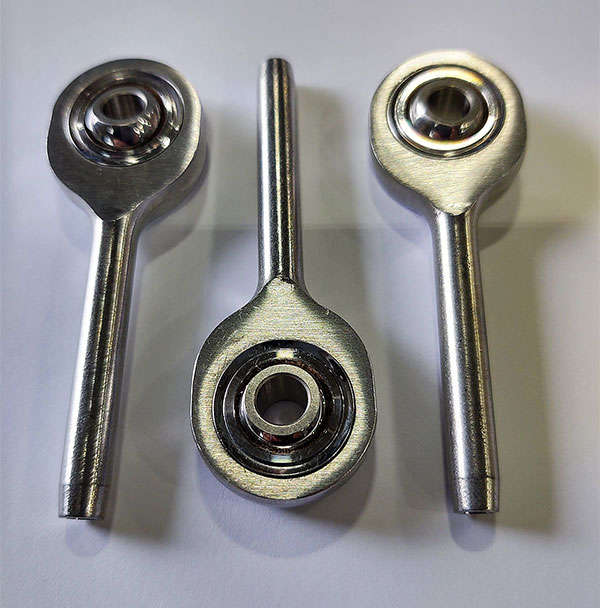 Three stainless steel ball bearings on a white surface.