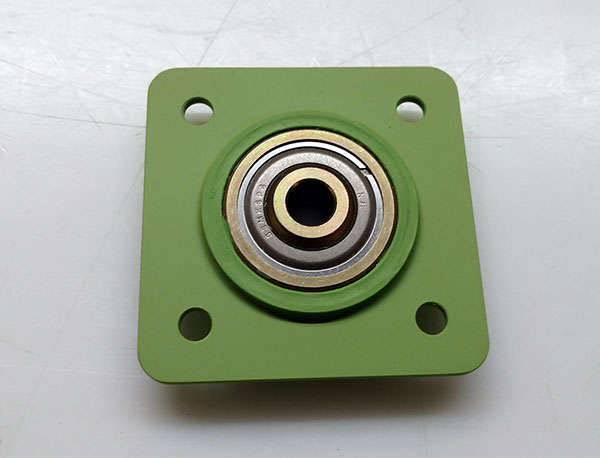 A green bearing with a metal plate on it.