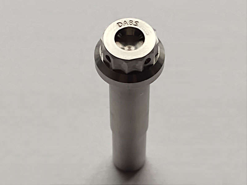 Manufacturing a stainless steel nut on a white surface.