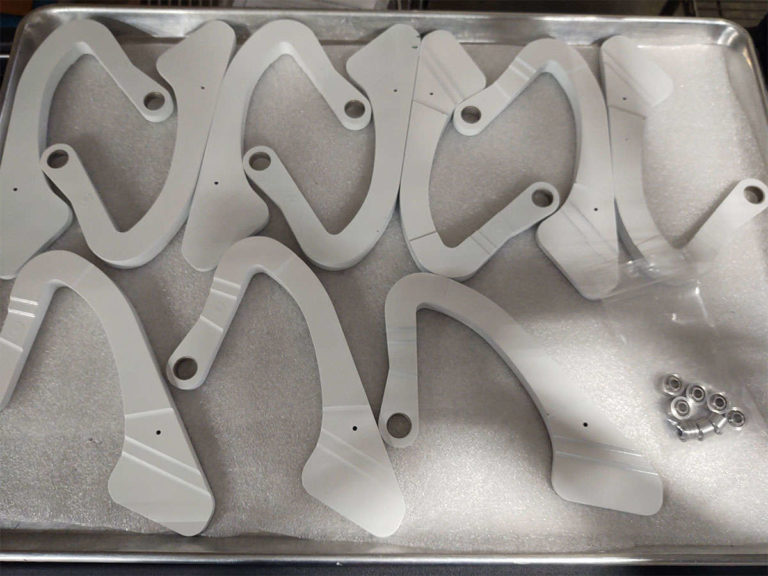 A tray of white plastic parts for assembly on a table.