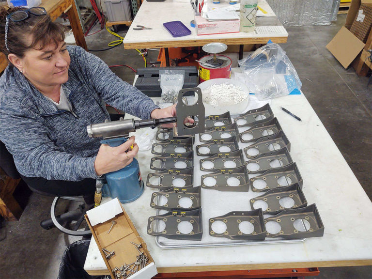 A woman assembling on a table in a workshop.