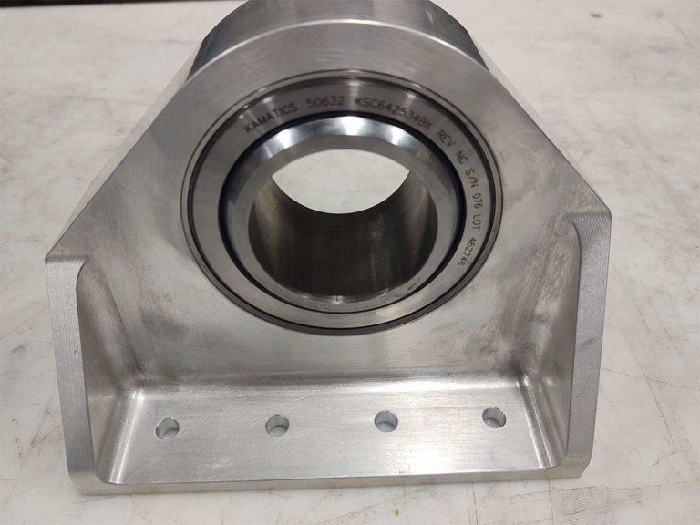 Assembly of a stainless steel bearing housing on a table.