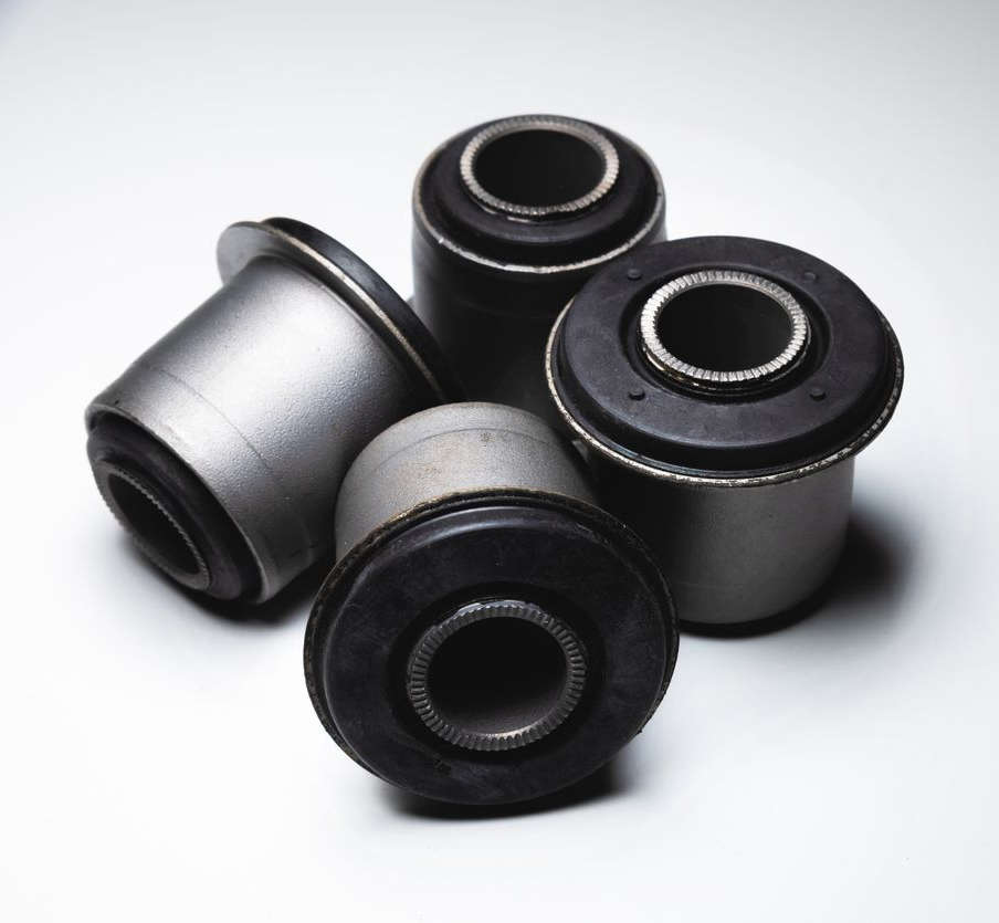 Four rubber bushings on a white surface, illustrating installation process.