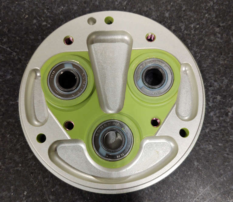 A green cover with two holes used for bushing installation.