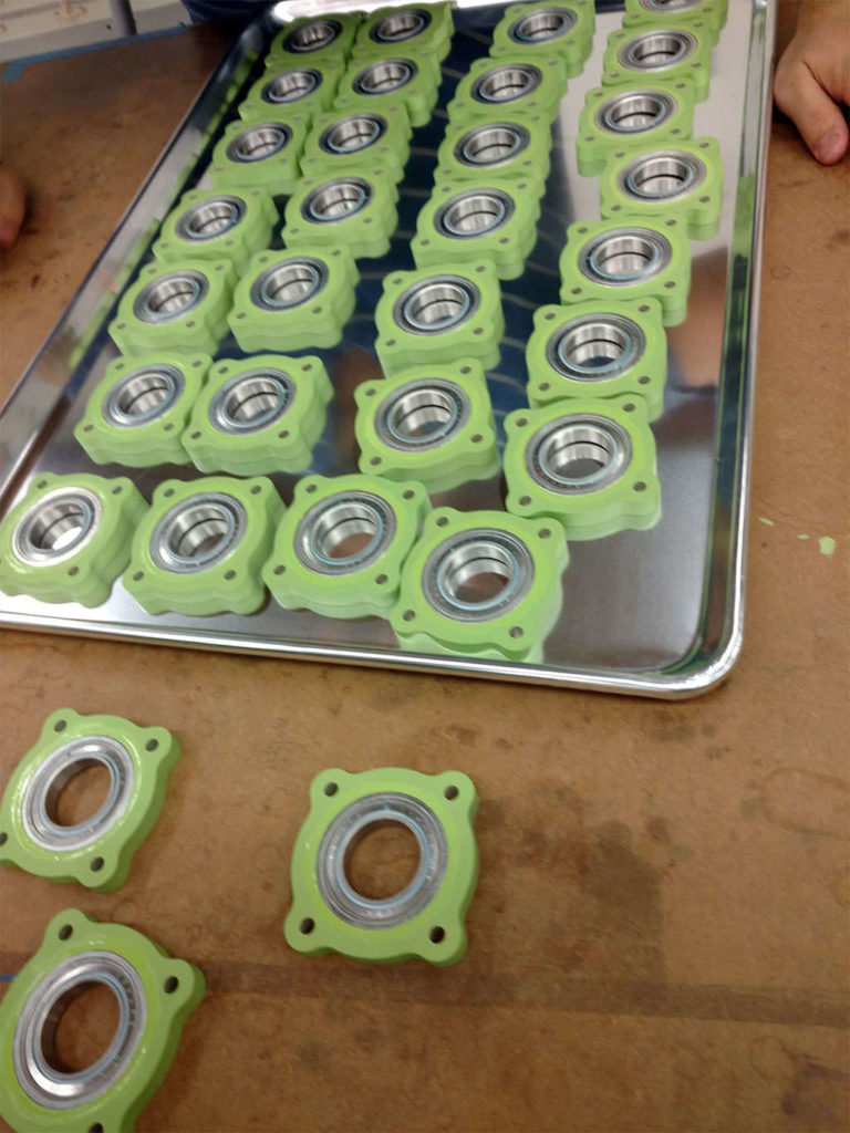 A tray of green bearings for bushing installation on a table.