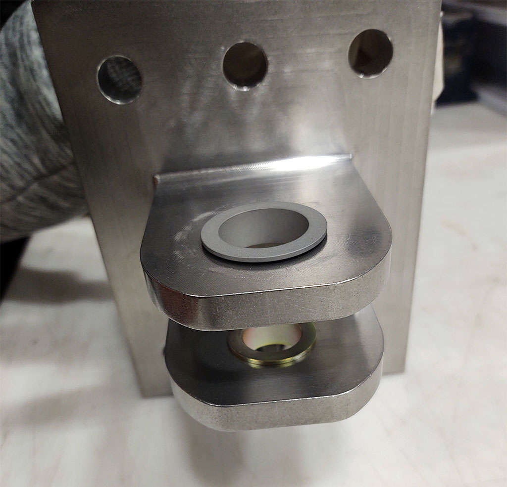A metal plate with a hole used for bushing installation.