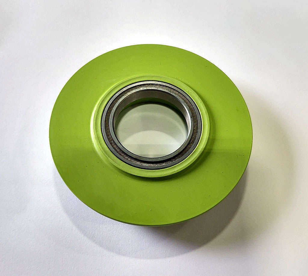 A green ball bearing for bushing installation on a white surface.